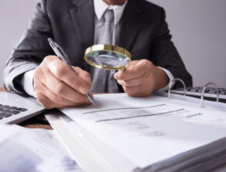 Análisis de auditoría financiera con lupa y documentos oficiales en oficina.